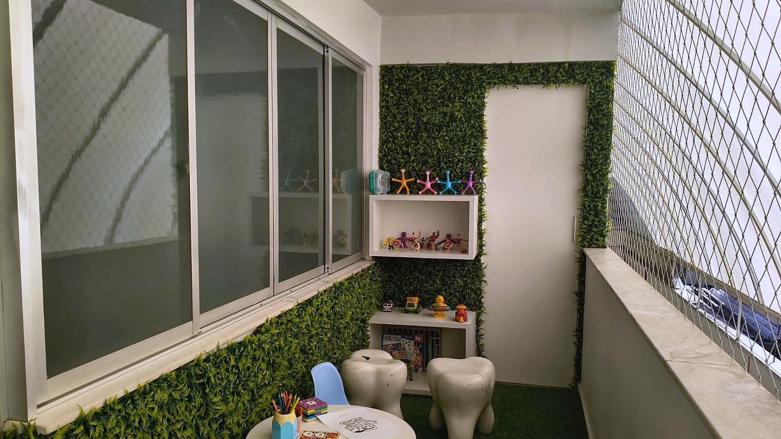 Espaço de espera infantil da unidade Floresta, com prateleiras de brinquedos, banquinhos em formato de dente e mesinha de desenho